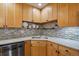 Corner kitchen view featuring wood cabinets, mosaic backsplash, stainless steel sink, and light countertops at 9836 W Freiburg Dr # 4E, Littleton, CO 80127