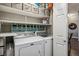 Functional laundry room with white washer and dryer, overhead shelving, and storage solutions at 9836 W Freiburg Dr # 4E, Littleton, CO 80127