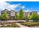 Modern condo building with a mix of brick and siding, balconies, and landscaped greenery under a bright blue sky at 7700 E 29Th Ave # 404, Denver, CO 80238