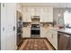 Well-lit kitchen featuring stainless steel appliances, white cabinets, and a stylish rug at 5687 Dayton St, Denver, CO 80238