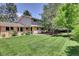Green backyard featuring mature trees, lush lawn, and an outdoor seating area at 7504 E Jefferson Dr, Denver, CO 80237