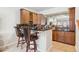 Home bar with wooden cabinets, black countertops, and bar stool seating at 4775 S Anaheim Ct, Aurora, CO 80015