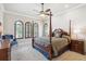 Spacious bedroom featuring a four-poster bed, ceiling fan, and three arched windows at 4775 S Anaheim Ct, Aurora, CO 80015