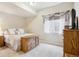 Comfortable bedroom features a bed, wooden dresser, carpet, and bright window with natural light at 4775 S Anaheim Ct, Aurora, CO 80015