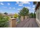 Spacious deck with iron railings overlooks a quiet street with green trees and blue skies above at 4775 S Anaheim Ct, Aurora, CO 80015