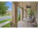 Inviting covered porch featuring stylish furniture and views of lush greenery and the peaceful street at 4775 S Anaheim Ct, Aurora, CO 80015
