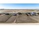 Full aerial view displaying the house, nearby sheds, neighboring houses, and empty, fenced plots at 7440 S Shenandoah Dr, Elizabeth, CO 80107