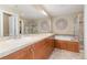 Bright bathroom features double sinks with wood cabinets, a large mirror, and a soaking tub with a separate glass shower at 9228 Sori Ln, Highlands Ranch, CO 80126