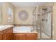 Bright bathroom features a glass enclosed shower, soaking tub, and decorative medallion on the light beige walls at 9228 Sori Ln, Highlands Ranch, CO 80126