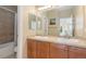 Spacious bathroom featuring double sink vanity with wood cabinets, and a shower/tub combo with neutral tile at 9228 Sori Ln, Highlands Ranch, CO 80126