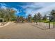 Community playground featuring swings, slides and play structures with mature trees on a resilient play surface under bright skies at 7790 W 87Th Dr # H, Arvada, CO 80005