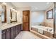 Bright bathroom featuring a soaking tub, vanity with double sinks, and decorative fixtures and tile surround at 16247 E Belleview Pl, Centennial, CO 80015