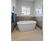 Modern bathroom with a freestanding tub, wood-look accent wall, and a window for natural light at 2741 Morning Run Ct, Franktown, CO 80116