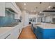 Modern kitchen featuring white cabinets, blue island, stainless steel appliances, and an eye-catching blue tile backsplash at 2741 Morning Run Ct, Franktown, CO 80116