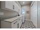 Well-lit laundry room with patterned tile, ample counter space, and sleek white cabinetry at 2741 Morning Run Ct, Franktown, CO 80116