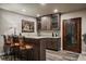 Stylish wet bar in basement with granite counters, wood cabinets, and seating at 2741 Morning Run Ct, Franktown, CO 80116