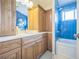 Bright bathroom featuring blue tile, wooden cabinets, and a shower-tub combo at 9361 Crestmore Way, Littleton, CO 80126