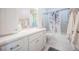 Bathroom featuring white cabinetry, white tile, and shower-tub combo at 9361 Crestmore Way, Littleton, CO 80126