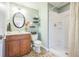 Bathroom with a wood vanity, oval mirror, and walk-in shower at 9361 Crestmore Way, Littleton, CO 80126
