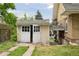 Detached garage with weathered white doors, showing potential for storage or a workshop space at 1551 S University Blvd, Denver, CO 80210