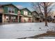 Townhome exteriors boast stone accents, painted siding, covered porches, and wintery front lawn and sky at dusk at 643 S Norfolk Way, Aurora, CO 80017