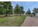 Lush backyard with mature trees, gravel area, and views of a charming barn at 36700 Mossberg Ct, Elizabeth, CO 80107