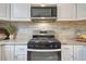 Close up of modern stainless steel microwave and gas range, with granite countertops and backsplash at 36700 Mossberg Ct, Elizabeth, CO 80107