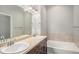 Bathroom featuring double sinks, a large mirror, and a soaking tub with tiled surround at 11250 Florence St # 29D, Commerce City, CO 80640