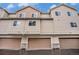 Exterior view of tan townhomes with attached garages featuring stone accents and neutral trim at 11250 Florence St # 29D, Commerce City, CO 80640