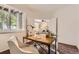 Comfortable office space leading into a living room, featuring a wooden desk, white walls, and hardwood floors at 4221 S Blackhawk Cir # 7G, Aurora, CO 80014