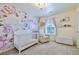 Charming Bedroom with floral wallpaper, crib, chair, and decorative shelves at 17341 Red Cosmos Pt, Parker, CO 80134