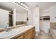Bathroom with double sinks, oak vanity, tile floors, toilet, and walk-in shower/bath combination at 4346 S Quail St, Littleton, CO 80127
