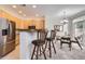 Open kitchen with stainless steel refrigerator, oak cabinets, granite countertops, breakfast bar, and dining area at 4346 S Quail St, Littleton, CO 80127