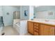 A well-lit bathroom featuring a soaking tub and shower, light blue walls, and wooden cabinets at 6606 S Reed Way # B, Littleton, CO 80123