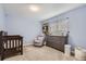 Cozy Bedroom with a wooden crib, gray dresser, comfortable armchair, and soft blue walls at 7640 S Monaco W Cir, Centennial, CO 80112