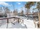 Snowy backyard with wooden deck and mature trees at 995 S Upham St, Lakewood, CO 80226