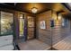 Inviting covered front porch and front door area with wood decking, decorative lighting, and cabin signage at 8140 Lightening View Dr, Parker, CO 80134