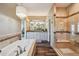 Bathroom featuring wood-look floors, glass shower, soaking tub and double vanity with large mirror at 12121 Bryant St, Westminster, CO 80234