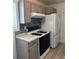 Cozy kitchen with gas range stove, white refrigerator, and grey cabinets and backsplash at 7620 Kearney Dr, Commerce City, CO 80022