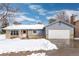 Charming single-story home featuring brick accents, an attached two-car garage and a well-maintained front lawn during winter at 1606 S Flanders Way, Aurora, CO 80017