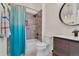 Bright bathroom featuring a shower with gray textured tiles and a vanity with a round mirror at 8747 Mesquite Row, Lone Tree, CO 80124