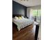 Modern bedroom featuring a large bed, dark blue accent wall, and sliding glass doors to a balcony at 8747 Mesquite Row, Lone Tree, CO 80124