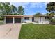 Inviting white brick home featuring an attached garage, lush lawn, and cozy front porch seating at 9197 W Woodard Dr, Lakewood, CO 80227