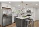 Modern kitchen features white cabinets, stainless steel appliances, and a stylish center island with bar stools at 9197 W Woodard Dr, Lakewood, CO 80227