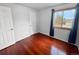 Simple bedroom with hardwood floors, blue curtains on the window, and a white closet door at 85 Yank Way, Lakewood, CO 80228