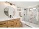 Updated bathroom with a modern vanity, round mirror, and tiled shower at 1892 S Fairfax St, Denver, CO 80222