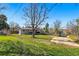 Expansive backyard with lush green grass, mature trees and a paved driveway offering outdoor space at 5390 Rosemary Ln, Denver, CO 80221