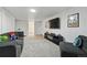Carpeted basement media room boasts a gray couch, a TV with art, and comfortable chair at 5390 Rosemary Ln, Denver, CO 80221