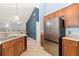 Modern kitchen with a stainless steel refrigerator, wooden cabinetry, granite countertops, and tiled floors at 8627 Gold Peak Pl # C, Highlands Ranch, CO 80130