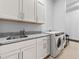Bright laundry room equipped with sink, granite countertops, and a new washer and dryer at 12947 Lazy Dog Ln, Littleton, CO 80127
